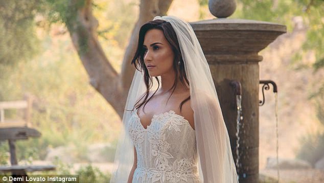 Demi Lovato’s fans go WILD after she poses as a blushing bride in full wedding dress and veil