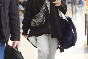 Rihanna goes ultra-casual as she strolls through JFK in grey sweats, fuzzy slippers and a baseball cap