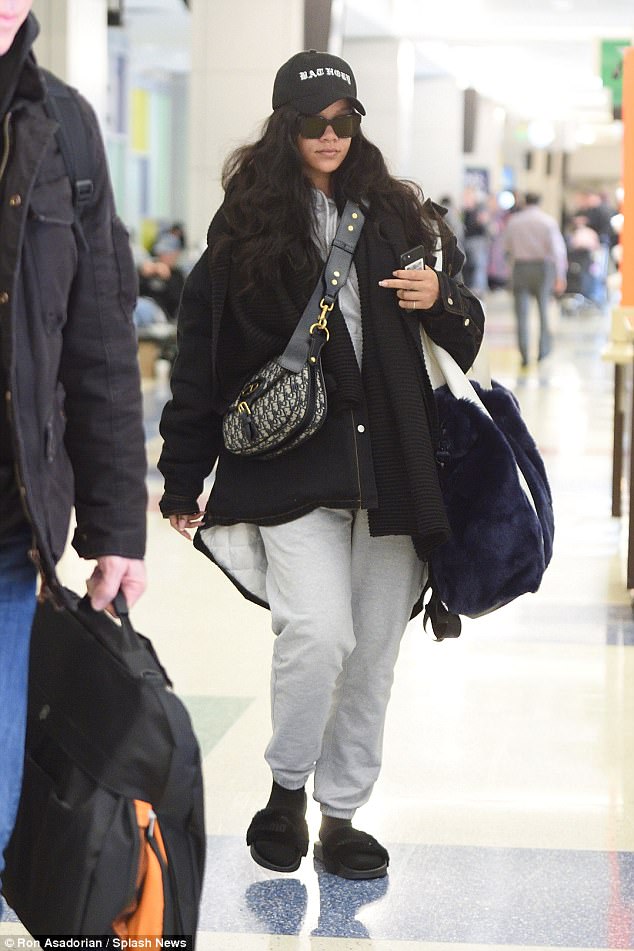 Rihanna goes ultra-casual as she strolls through JFK in grey sweats, fuzzy slippers and a baseball cap